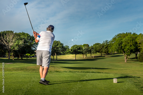 Man teeing off in the tee box, playing golf