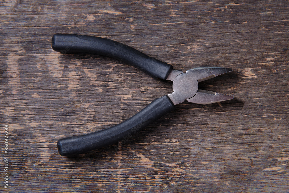 Pliers with plastic handles on a wooden background, top view Pliers with plastic handles on a wooden background, top view