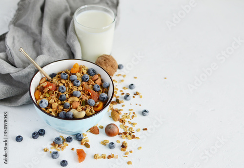 homemade granola in bowl with milk, nuts, dried apricots, blueberries. Healthy vegetarian breakfast. The concept of diet, proper nutrition, fitness diet. Losing weight.copy space