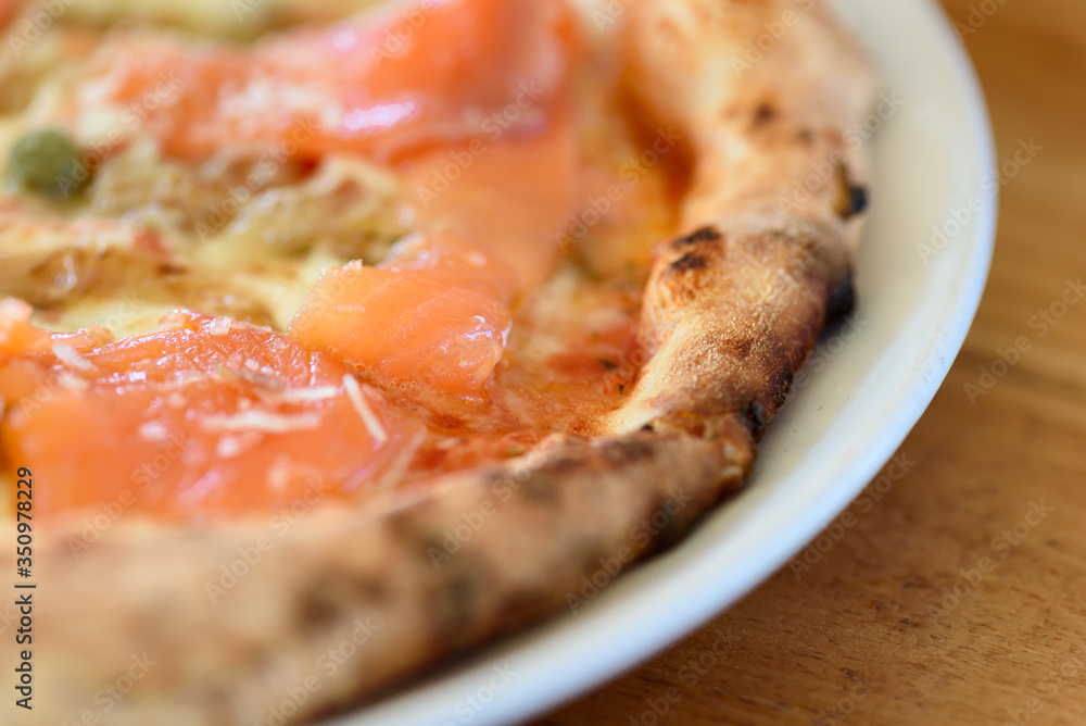 Homemade pizza with capers on a wood table