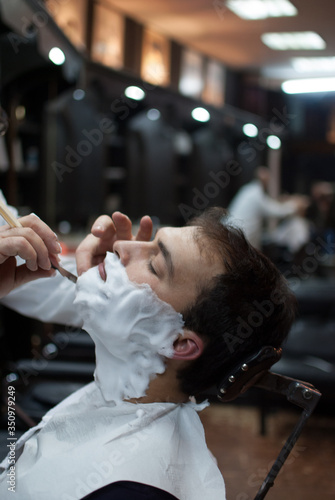 Young and handsome man at a barbershop shaving