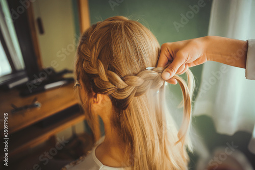 A side view of a woman makes a bridal hairstyle. Wedding hair salon. Close-up of a hairdresser and a bride