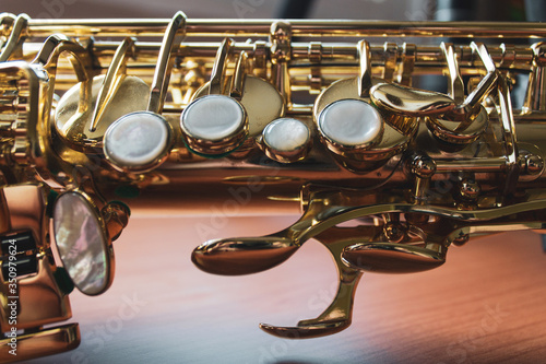 Closeup of saxophone keys on a wood surface.