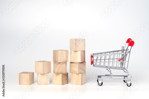 Graphs chart wooden cube block and trolley cart on a white background. Shopping, sale, finance, and business concept. 