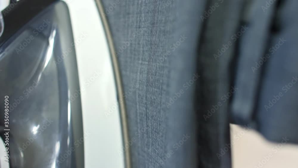 Female hands are ironing clothes that hangs on the railing, steams in vertical situation, a professional iron with steam, sewing production. Female hands are ironing clothes that hangs on the railing, steams in vertical situation, a professional iron with steam, sewing production.
