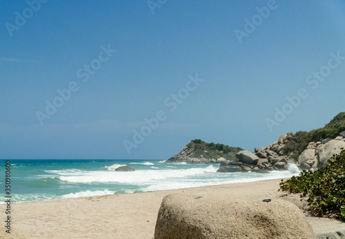 Playa con mar azul y grandes monta  as de rocas