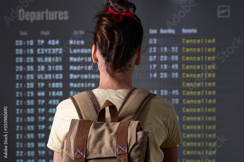 young tourist looking cancelled flights in departure screens at airport photo