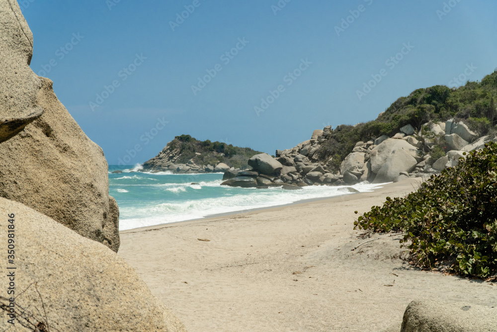 Playa con mar azul y grandes montañas de rocas