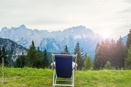 The man in the chair admires the view of the mountains.