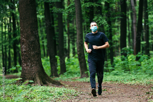 Runner wearing medical mask. Coronavirus pandemic Covid-19 a man in a medical mask runs in the forest © Ruslan Ivantsov