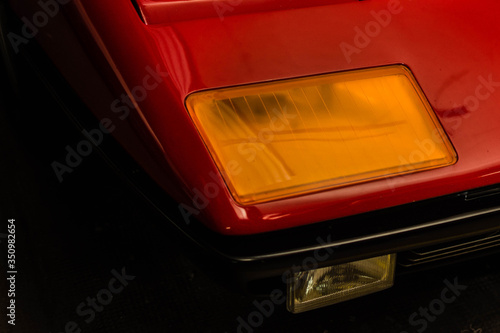 Close-up view of headlight of classic Italian supercar. Red car, zero style, vintage. © Jonathan