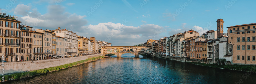 Medieval bridge Ponte Vecchio (Old Bridge) and the Arno River, Florence, Tuscany, Italy. Florence is a popular tourist destination of Europe. Panoramic shot. Sunset light.