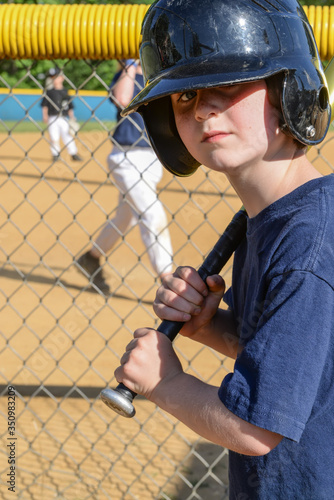 Cute boy with a dark blue baseball helmet on holding a bat.