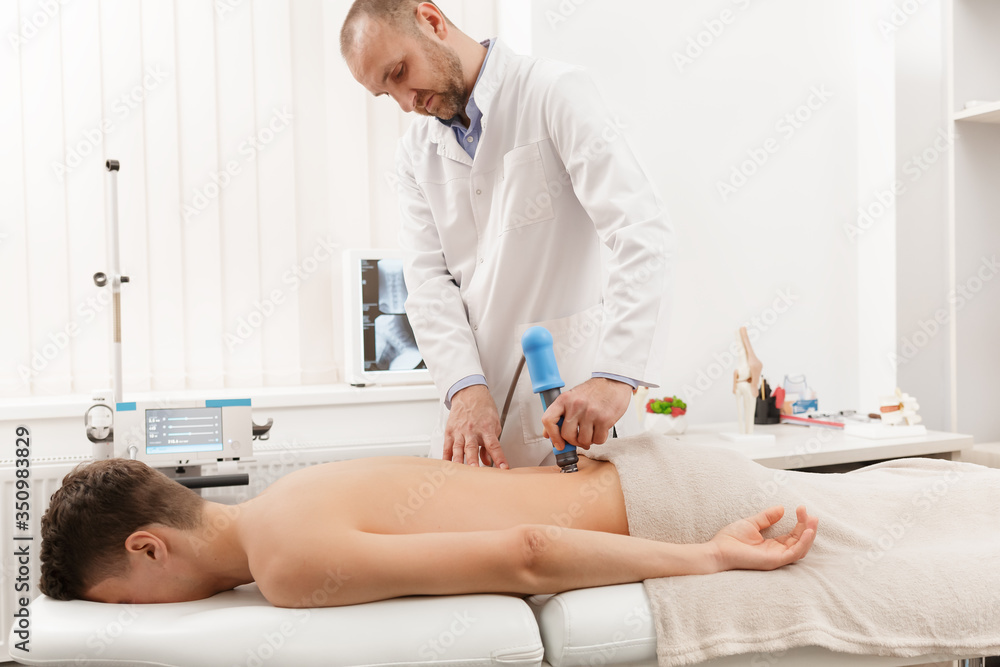 Obraz premium Extracorporeal Shockwave Therapy ESWT.Effective non-surgical treatment.Physical therapy for lower back with shock waves.Pain relief, normalization and regeneration,stimulation of healing process.