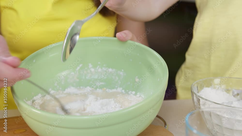 Close up of a cook mixing flour for dough. A child's hand pours flour into a salad bowl to make flour Close up of a cook mixing flour for dough. A child's hand pours flour into a salad bowl to make flour