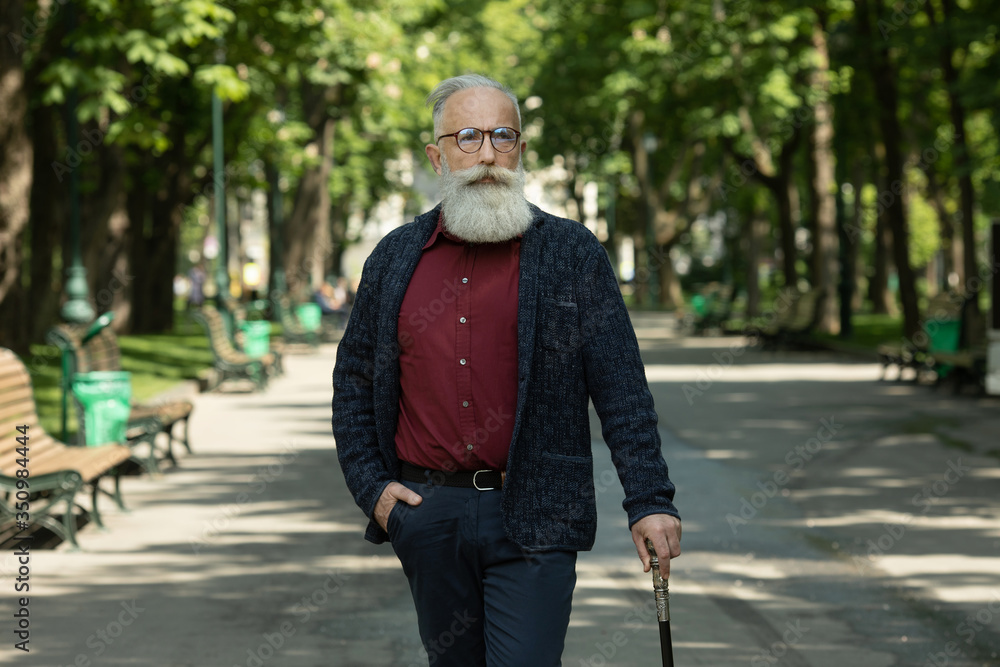 Content senior man with a beard and wearing glasses outdoor. Content senior man with a beard and wearing glasses outdoor.