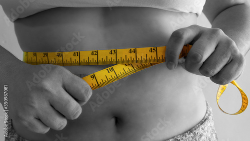 cinta métrica amarilla midiendo cintura femenina