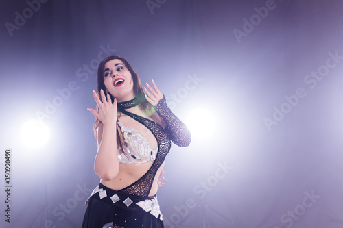 Young woman belly dancer in exotic dress with gold, dancing tribal fusion dance in studio. Copy space. © satura_