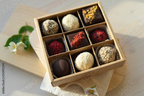 A box of chocolate mix of chocolates stands on the table in the morning light. Beautiful sweet gift for the wedding, for the birthday, for the holiday