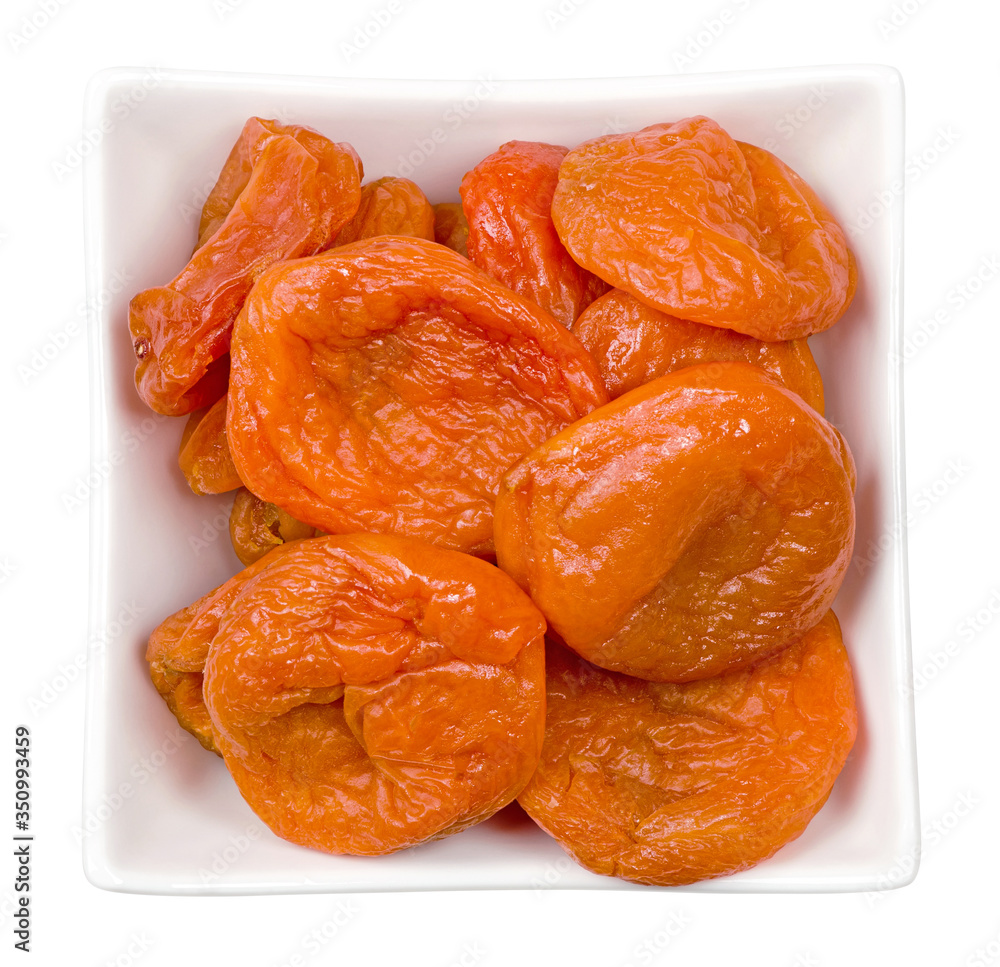 Isolated dried apricots. Bowl of dried apricots isolated on white background with clipping path. Top view. Isolated dried apricots. Bowl of dried apricots isolated on white background with clipping path. Top view.