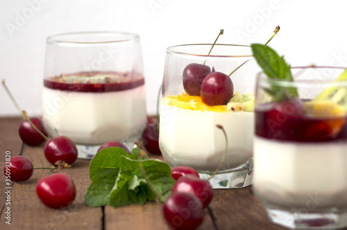 three types of milk jelly Panna cotta in glass glasses decorated with cherries