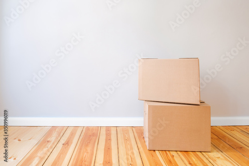 two cardboard boxes in empty room with wall background and copy space, moving in new flat concept mockup