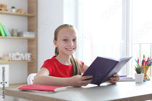 little girl reads a book at home
