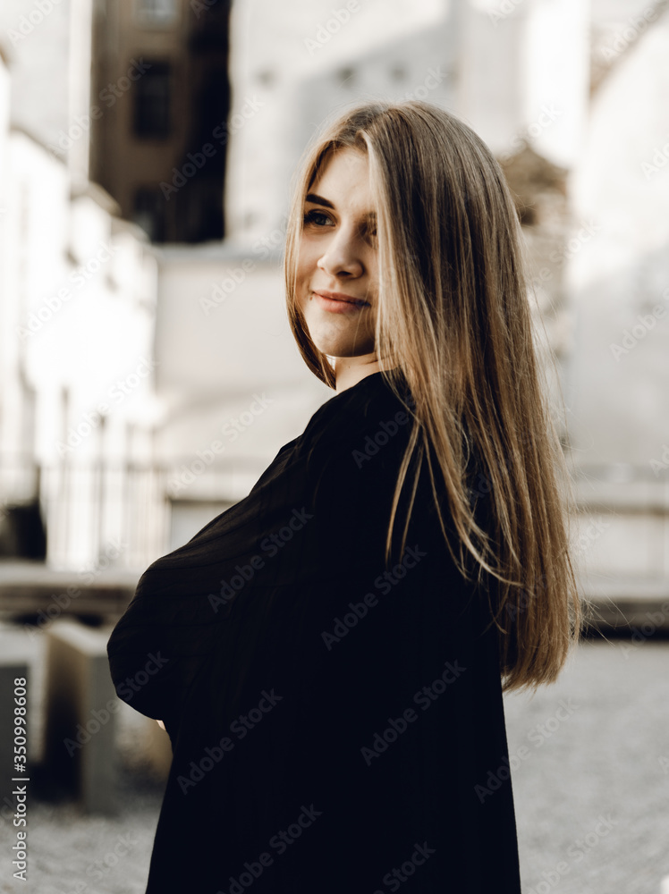 a beautiful young girl in a black dress with chic shiny hair posing and smiling at the camera; the girl waves her hair; dreamy mood a beautiful young girl in a black dress with chic shiny hair posing and smiling at the camera; the girl waves her hair; dreamy mood