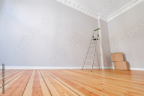 empty room after renovation with ladder and cardboard boxes -