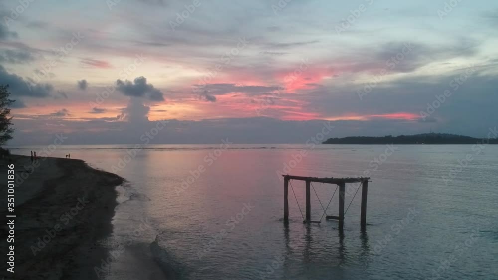 colorful red sunset on a background of a swing in the ocean an island is visible colorful red sunset on a background of a swing in the ocean an island is visible