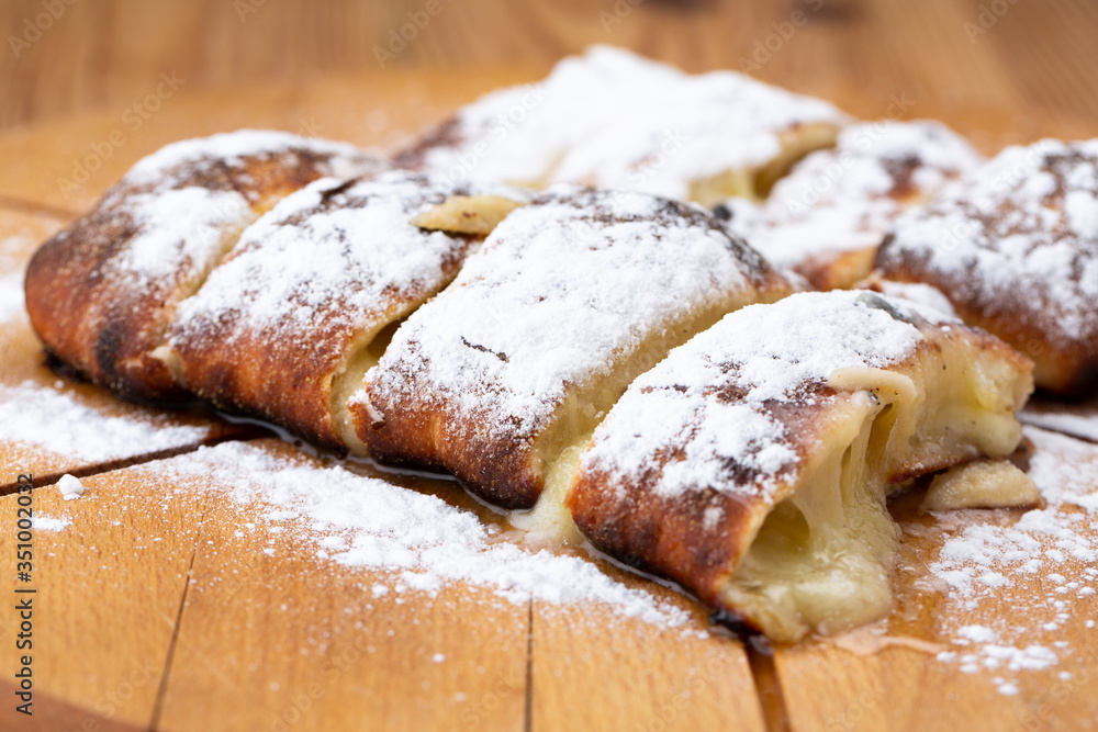 fruit strudel on a wooden board sprinkled with icing sugar. delicious pastries
