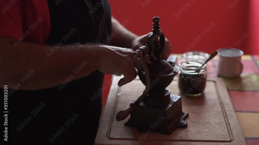 unrecognizable man grinding coffee in an ancient manual mill to make good coffee, side view unrecognizable man grinding coffee in an ancient manual mill to make good coffee, side view