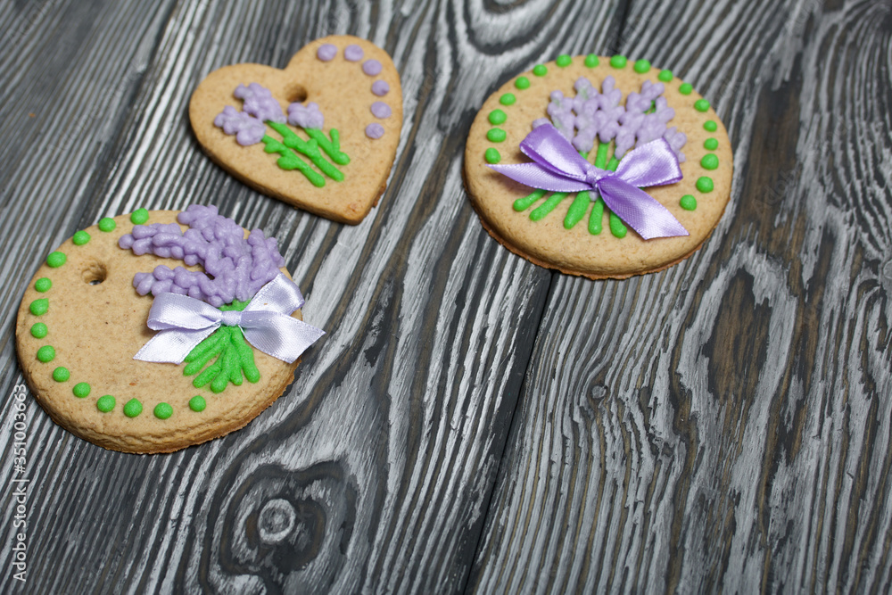 Gingerbread cookies decorated with glaze. On some ribbons tied to a bow. Gingerbread cookies are round and in the shape of a heart. On brushed pine boards.