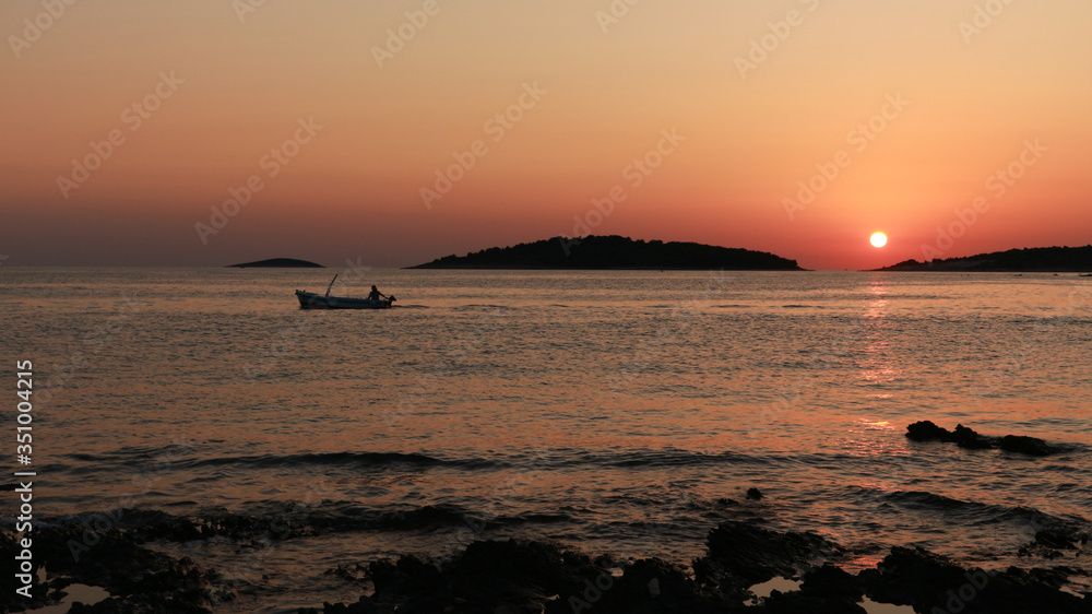 Single fisherman sailing out to the sea at sunset to catch fish on the open sea at Croatian side of Adriatic coast in a small fishing town of Rogoznica