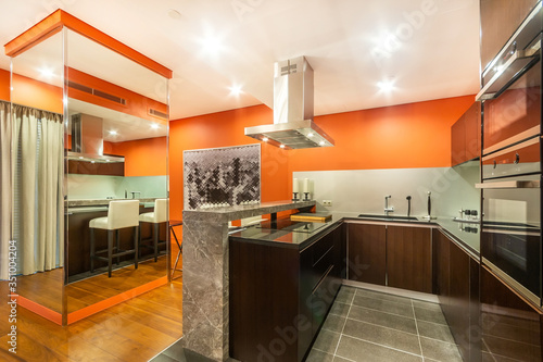 Orange kitchen with a marble counter  equipped with cooker  oven  fridge