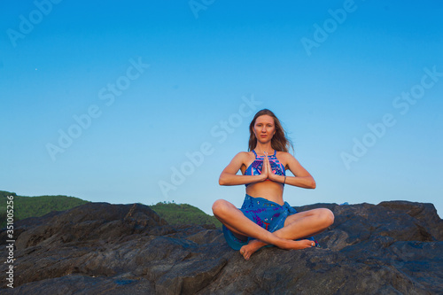 a beautiful woman meditates on a rock