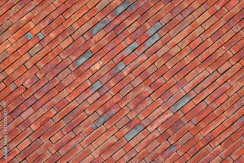 Photo of a sloping red brick wall. Red stone wall  background  texture. Old red brick wall texture background.