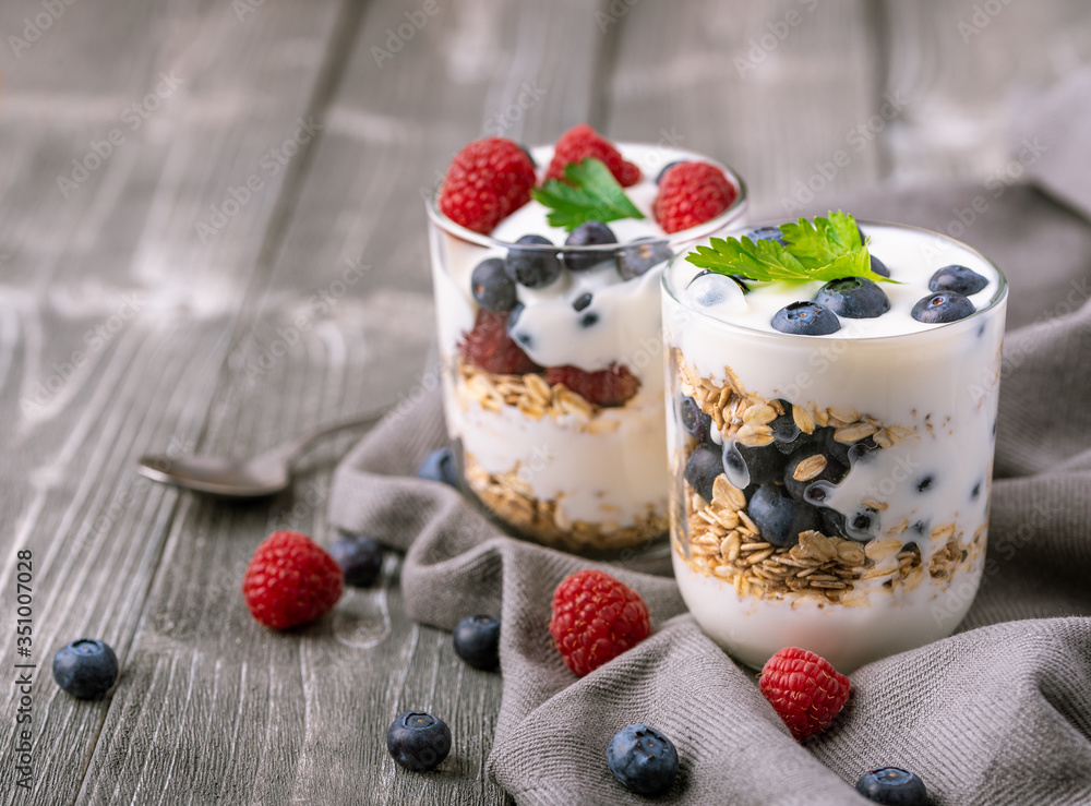 White yogurt in glass jar with fruits on grey background. White yogurt in glass jar with fruits on grey background.