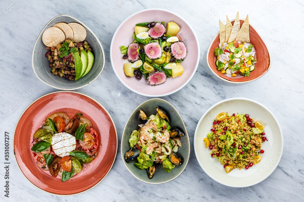 Few plates with different salads on the white background Few plates with different salads on the white background