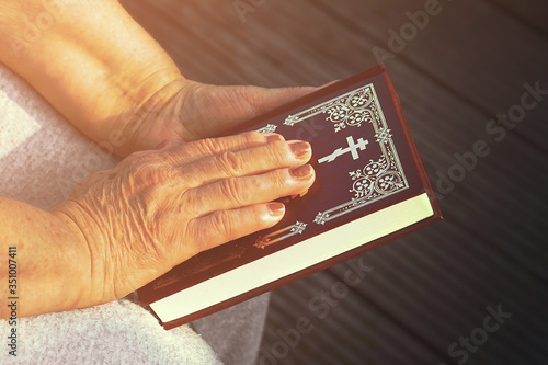 Hand of elderly woman lies on an a Bible, woman praying. Woman hand with Bible praying, Hand in prayer on a Holy Bible in church concept for faith, spirituality and religion.