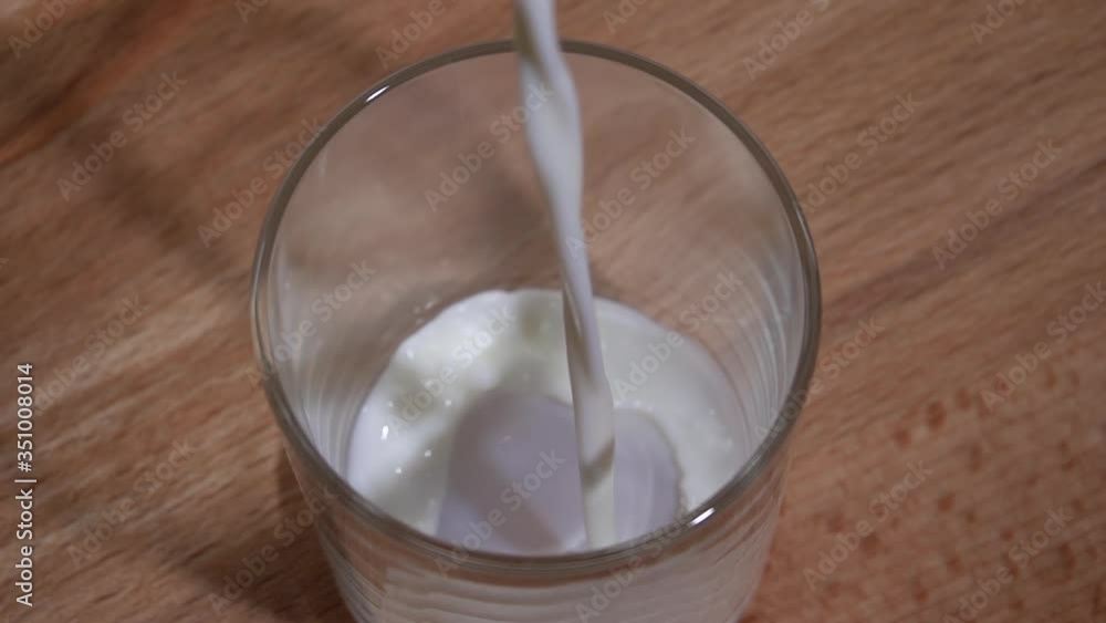 Milk is poured into a glass on a wooden table. Slow motion 250fps Milk is poured into a glass on a wooden table. Slow motion 250fps
