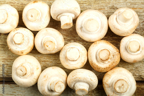 Fresh champignon mushrooms lie on a wooden table.