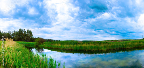 Landscape of a small pond during a cloudy sunset, panorama of the nature of the country