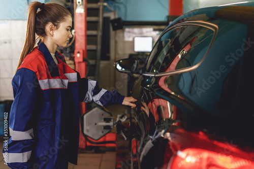 smart brunette woman examining her car, service concept. close the portrait. working day at the garage.