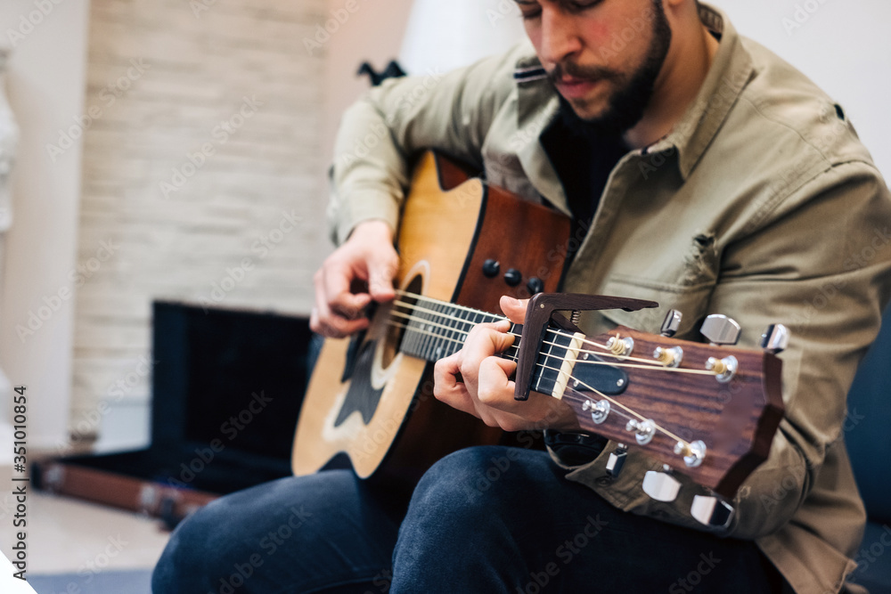 Obraz premium musico aprendiendo a tocar la guitarra en casa con el portatil