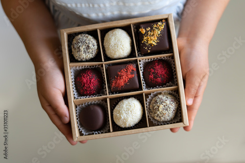 In the hands of a box of chocolates holds. assorted chocolates confectionery in their gift box on the white background