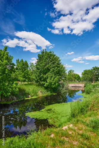 Blue and cloudy sky over a little creek in the surrounding countryside of Berlin  Germany.