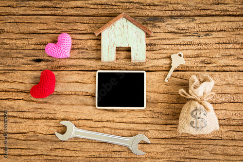 Wooden house and a heart and a money bag and a blackboard for copy space on the wooden vintage background, home loan for build or repairs concept.