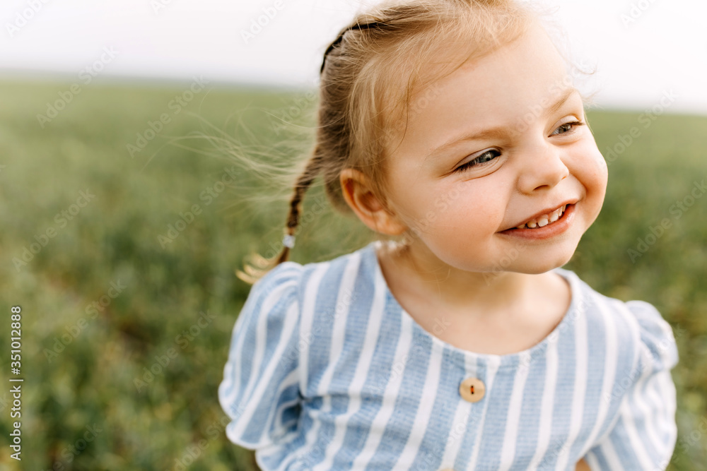 Little blonde girl with two braids close-up portrait, making funny face, smiling Little blonde girl with two braids close-up portrait, making funny face, smiling