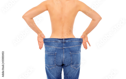 Slender girl in big jeans on a white background. Losing weight.